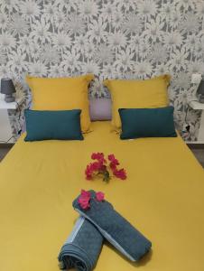 Una cama amarilla con almohadas amarillas y flores. en Le Hameau de la Ravine, en Saint-Pierre