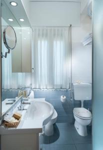 a bathroom with a sink and a toilet and a mirror at Hotel Astoria in Cervia