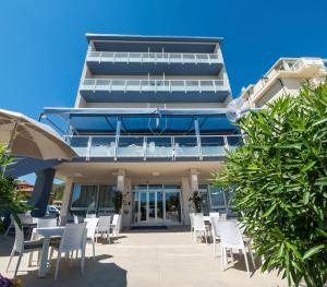 a building with tables and chairs in front of it at Hotel Astoria in Cervia