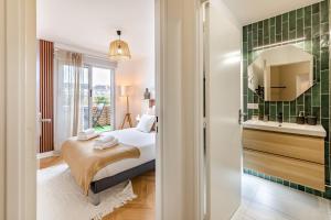 een slaapkamer met een bed en een badkamer met een wastafel bij Le Dobrée - Centre - Charme & Confort - 4p - 55m2 in Nantes