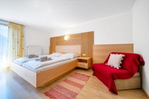 1 dormitorio con 1 cama y 1 silla roja en am mühlbach - einfach sein mit Gemeinschaftsküche und freien Eintritt in das Solarbad Dorfgastein, en Dorfgastein