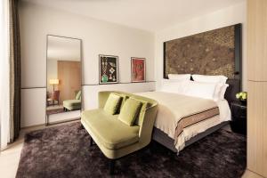 a bedroom with a bed and a chair and a mirror at Bulgari Hotel Milano in Milan