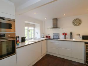 a kitchen with white cabinets and a clock on the wall at The Old Bakehouse in Oakham