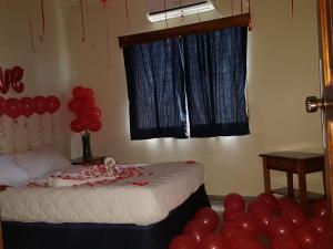 1 dormitorio con 1 cama con globos rojos en la esquina en Hotel Mango Cafe, en Tela