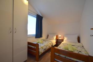 two beds in a small room with a window at Apartments Cindric in Malinska