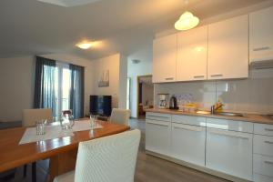 a kitchen with a wooden table and white cabinets at Apartments Cindric in Malinska