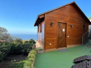 ein Holzgebäude mit einer großen Tür auf einem grünen Hof in der Unterkunft Cozy Mountain Chalet in La Orotava