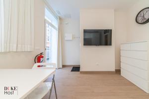 ein Wohnzimmer mit einem Tisch und einem TV an der Wand in der Unterkunft Marqués de Vadillo1 Apartments in Madrid