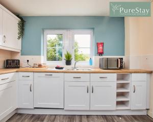 una cucina con armadietti bianchi e una finestra di Stunning 6-Bedroom House in Nantwich with Parking & Free Wi-Fi by PureStay Short Lets a Nantwich