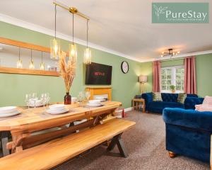 a living room with a table and a blue couch at Stunning 6-Bedroom House in Nantwich with Parking & Free Wi-Fi by PureStay Short Lets in Nantwich