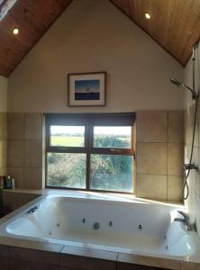 eine große weiße Badewanne im Bad mit Fenster in der Unterkunft Ocean Winds in Wexford