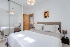 a white bedroom with a large bed and a mirror at Casa Alma - V027 in Lagos