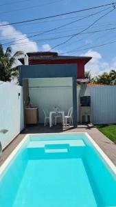 uma piscina azul com mesa e cadeiras em casa confortável em Camaçari
