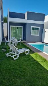 um quintal com duas espreguiçadeiras e uma piscina em casa confortável em Camaçari