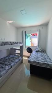 um quarto com 2 beliches e uma cadeira em casa confortável em Camaçari