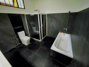 a bathroom with a shower and a toilet and a sink at Fortress Gate Bungalow in Polonnaruwa