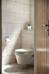 biała łazienka z toaletą i rośliną w obiekcie Remarkable 4-Bed House Near Leeds Airport w mieście Yeadon