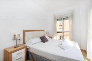 ein Schlafzimmer mit einem großen weißen Bett und einem Fenster in der Unterkunft The 1st Corner Central Apartments in Málaga