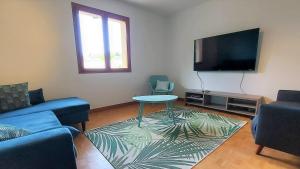 ein Wohnzimmer mit einem Sofa, einem Tisch und einem TV in der Unterkunft Le PRINTEMPS Grande villa familiale 10 pers in Annecy