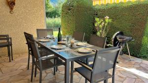 einen schwarzen Tisch mit Stühlen und eine Flasche Wein in der Unterkunft Le PRINTEMPS Grande villa familiale 10 pers in Annecy