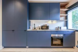 een keuken met blauwe kasten en een magnetron bij AmazINN Places Palacio Real in Madrid