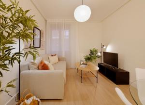 a living room with a white couch and a tv at Emilio Tuya 60 in Gijón