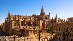 un gran edificio con palmeras delante en Casa Venus - con jardín y piscina, en Alcalá de Guadaira