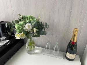 - une bouteille de champagne et un vase de fleurs sur une table dans l'établissement Ferme du Château Fontaine, à Fontaine-lʼÉvêque