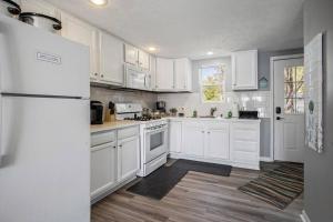 uma cozinha com armários brancos e um frigorífico branco em Enchanting Lake House on GunLake em Wayland