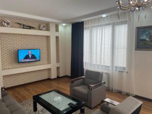 a living room with a couch and a tv on a wall at Beautiful Guest House Qusar in Qusar