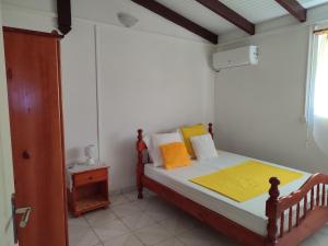 ein kleines Schlafzimmer mit einem Bett mit orangefarbenen und gelben Kissen in der Unterkunft Villa de la montagne in Pointe-Noire