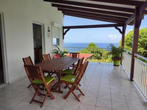 einen Holztisch und Stühle auf einem Balkon mit Meerblick in der Unterkunft Villa de la montagne in Pointe-Noire