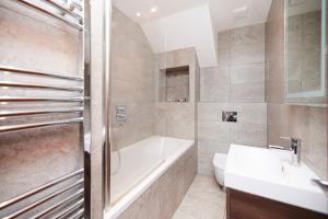 a bathroom with a tub and a toilet and a sink at The Wandsworth Haven - Bright 2BDR Flat in London