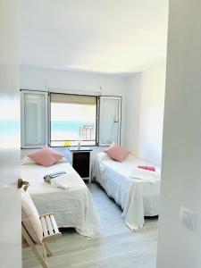a bedroom with two beds and a window with the ocean at Puerta al Mediterráneo in Jávea