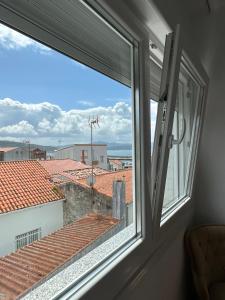 a window with a view of the roofs at CasaLola - Corme Porto in A Coruña