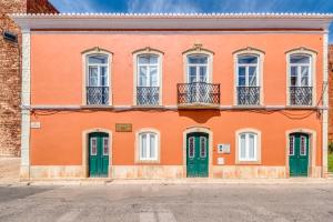 an orange building with green doors on a street at Casa Riad Yasmin in Silves
