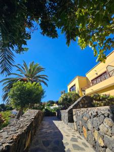 einen Steinweg, der zu einem Gebäude mit einer Palme führt in der Unterkunft Apartamentos Corral de Payo in Breña Baja