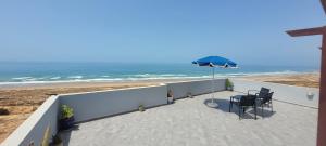 un patio con sedie e ombrellone e la spiaggia di Magnifique villa face à l'océan a Tiznit