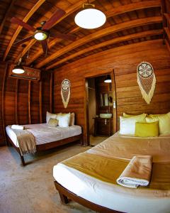 a bedroom with two beds in a room with wooden walls at Cabañas Coconut by MIJ in Holbox Island