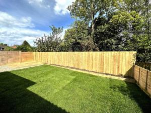 a backyard with a wooden fence and green grass at Seaside Snug - Gorgeous 2 Bed Seaside Bungalow in Hornsea