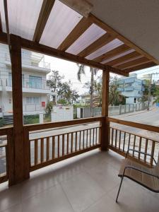 a wooden balcony with a chair and a view of a street at Apartamentos Lagoinha in Bombinhas