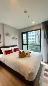 una camera da letto con un grande letto bianco con una grande finestra di The base Central Pattaya by Numam 38 a Centro di Pattaya