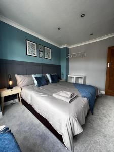 a bedroom with a large bed with blue walls at Leyland House, 3 Bedroom, Parking Space, Coventry CV5 in Allesley