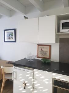 eine Küche mit weißen Schränken und einer schwarzen Arbeitsplatte in der Unterkunft BRISE MARINE in Groix