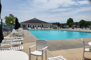 una piscina con sillas blancas y un edificio en Assateague Pointe - Helmsman en Berlin