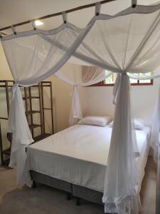 a bedroom with a canopy bed with white sheets and pillows at Acalanto do Sargi in Uruçuca