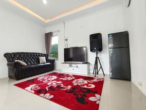 a living room with a black couch and a red rug at Villa Cisarua RJS in Brujul