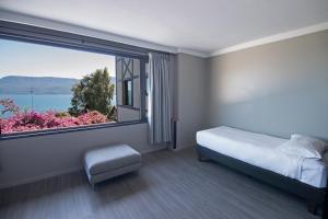 Hotel Enjoy Pucon في بوكون: غرفة نوم بسرير ونافذة كبيرة