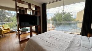 um quarto com uma grande janela com uma cama e uma televisão em Suite Picchu Picchu em Arequipa