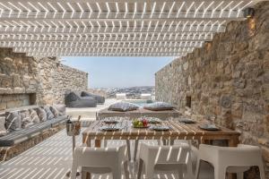 Mykonos Actor’s Villa. 2 BDRs, private mini-pool في مدينة ميكونوس: فناء مع طاولة وكراسي وجدار حجري